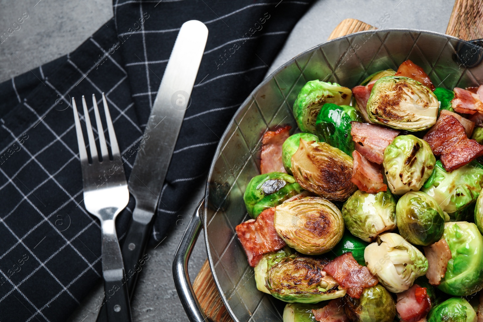 Photo of Delicious Brussels sprouts with bacon served on grey table, flat lay