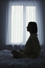 Photo of Beautiful pregnant woman sitting on bed at home