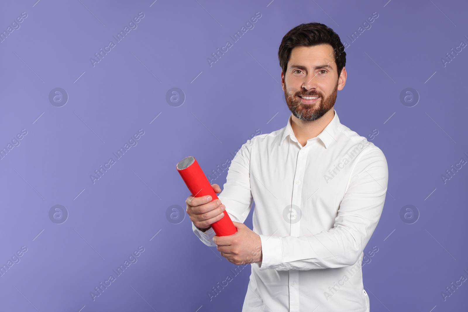 Photo of Happy man with party popper on violet background. Space for text