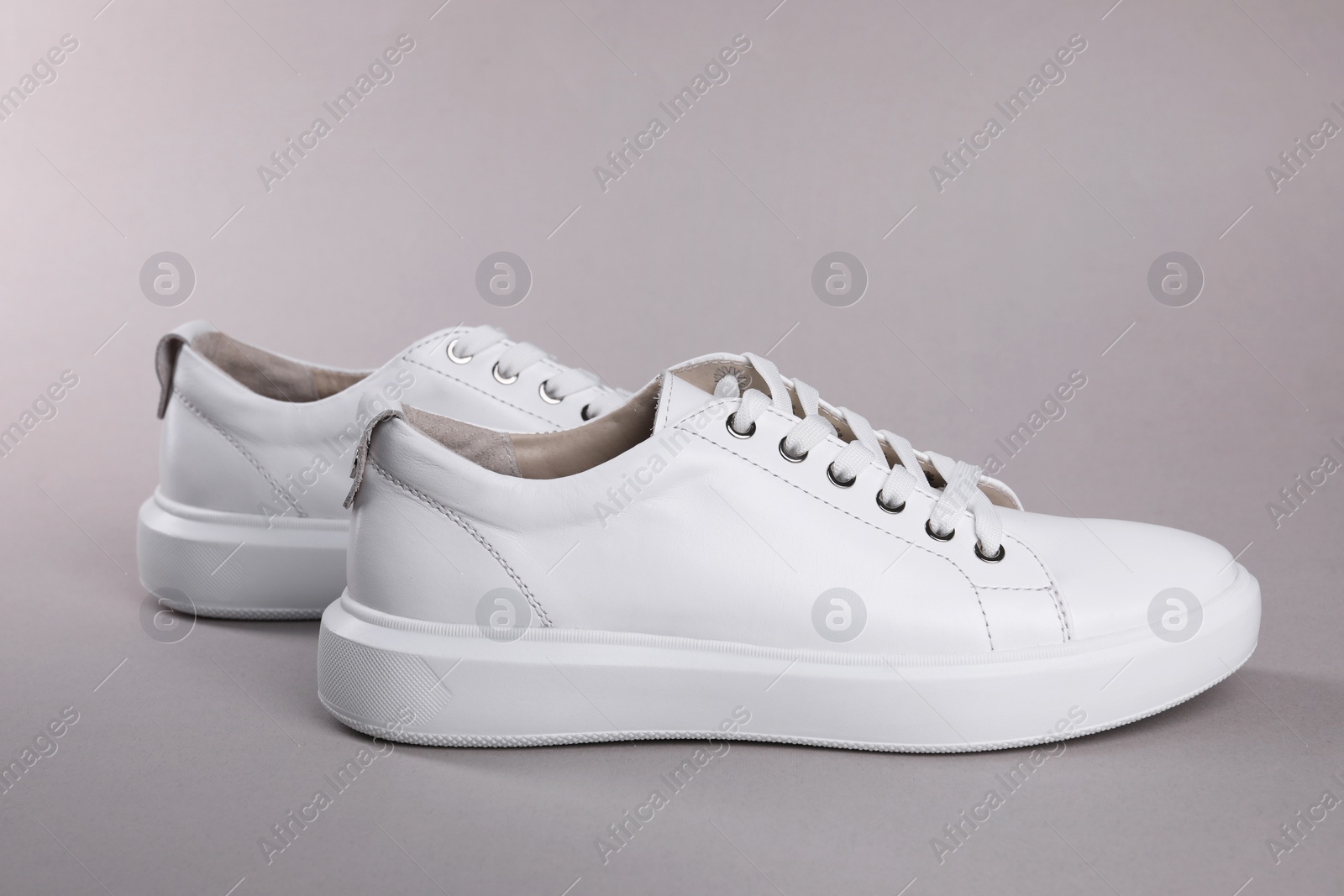 Photo of Pair of stylish white sneakers on grey background