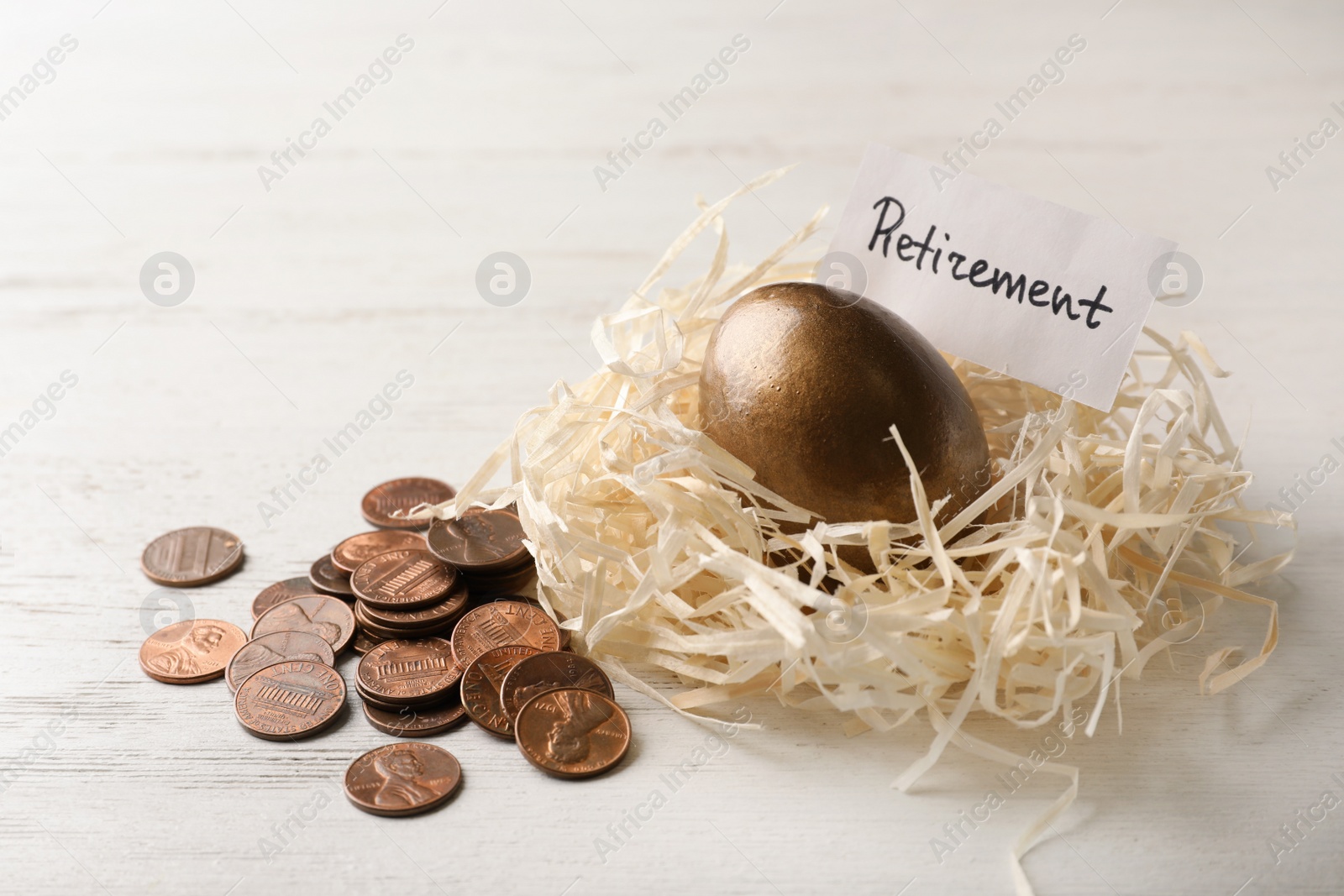 Photo of Golden egg and card with word RETIREMENT in nest near coins on wooden background. Pension concept