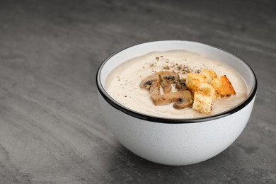 Photo of Delicious cream soup with mushrooms and croutons on black table. Space for text