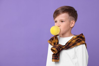 Boy blowing bubble gum on purple background, space for text