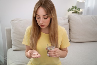 Young woman with abortion pill and water indoors