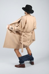 Photo of Exhibitionist exposing naked body under coat on light background, back view