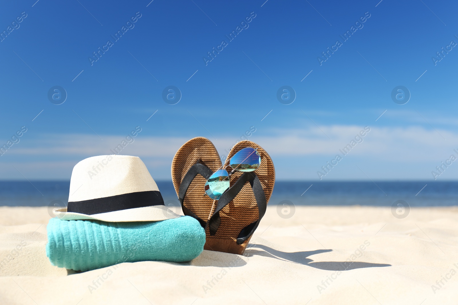 Photo of Stylish beach accessories for summer vacation on sand near sea. Space for text