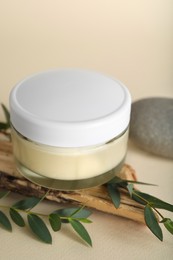 Photo of Composition with jar of body cream and eucalyptus on beige background, closeup