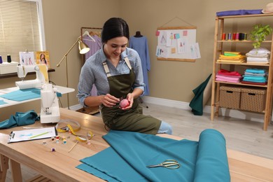 Photo of Dressmaker with pin cushion in modern workshop