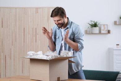 Emotional man opening parcel at home. Internet shopping