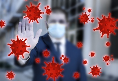 Image of Be healthy - boost your immunity. Man in protective mask showing stop gesture to viruses outdoors, focus on hand
