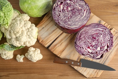 Flat lay composition with different cabbages on wooden background