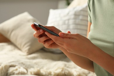 Photo of Woman with smartphone on sofa, closeup view