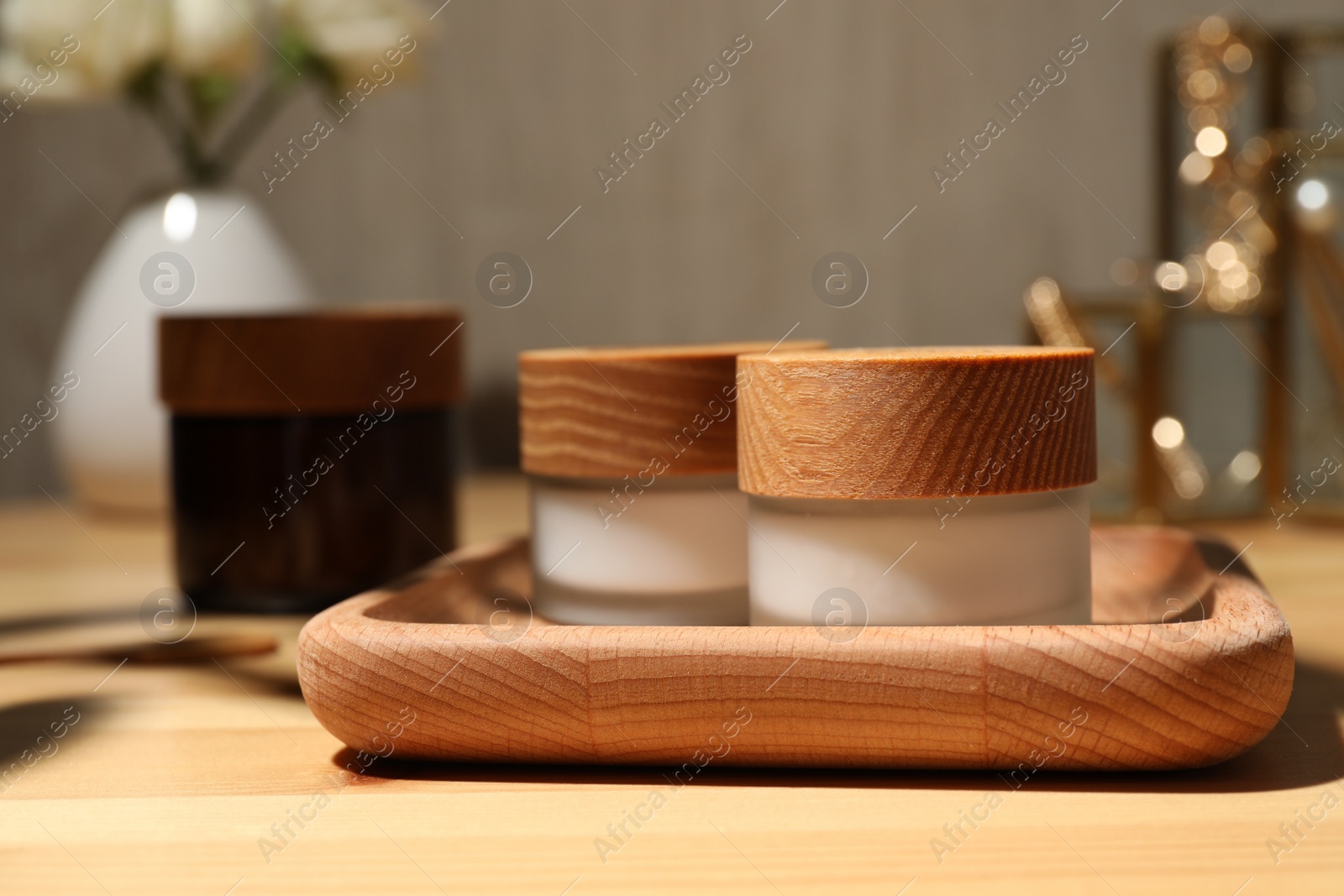 Photo of Jars of cream and tray on wooden table, closeup