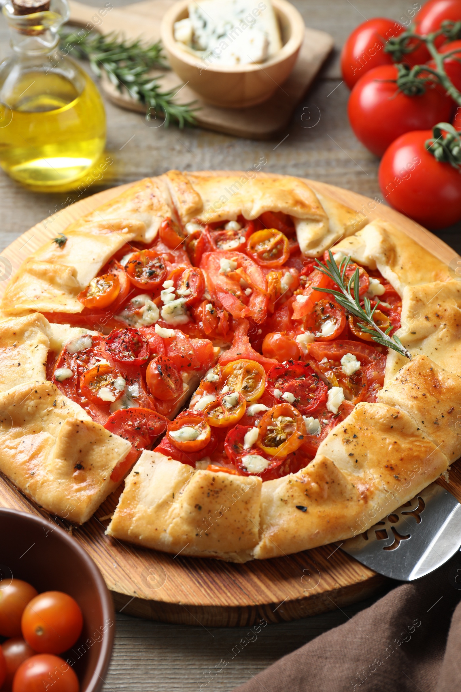 Photo of Tasty galette with tomato, rosemary and cheese (Caprese galette) on wooden table, closeup