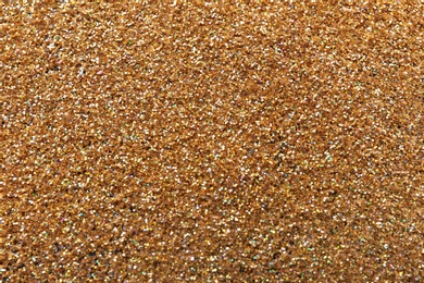 Photo of Texture of gold glitter as background, closeup