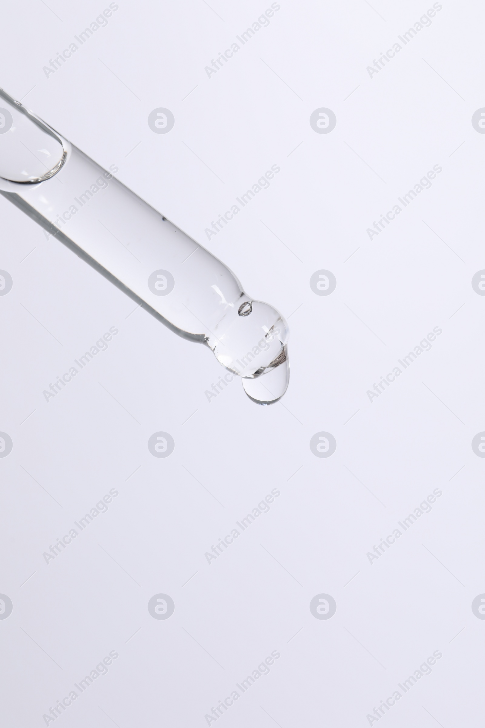Photo of Dripping cosmetic serum from pipette on white background