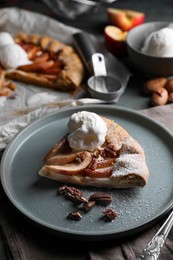 Photo of Delicious apple galette with ice cream and pecans on wooden table