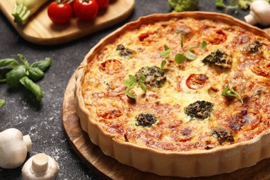 Delicious homemade vegetable quiche, oregano and mushrooms on black table, closeup