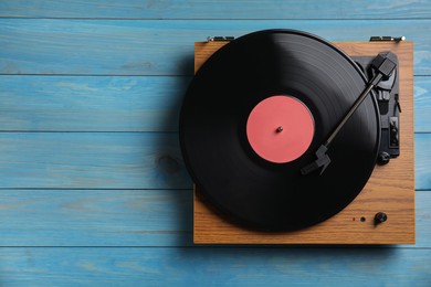 Photo of Modern vinyl record player with disc on blue wooden background, top view. Space for text