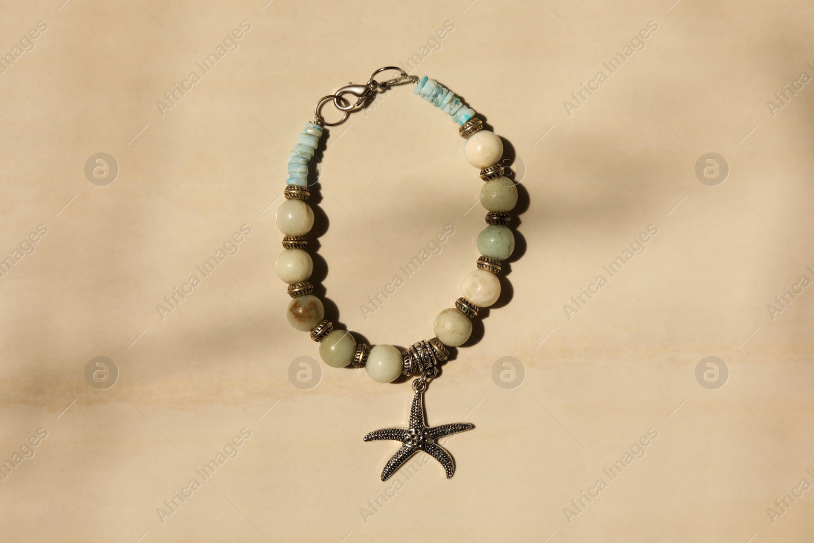 Photo of Beautiful bracelet with different gemstones on beige background, top view