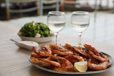 Photo of Plate of delicious cooked shrimps served with lemon and wine at table outdoors