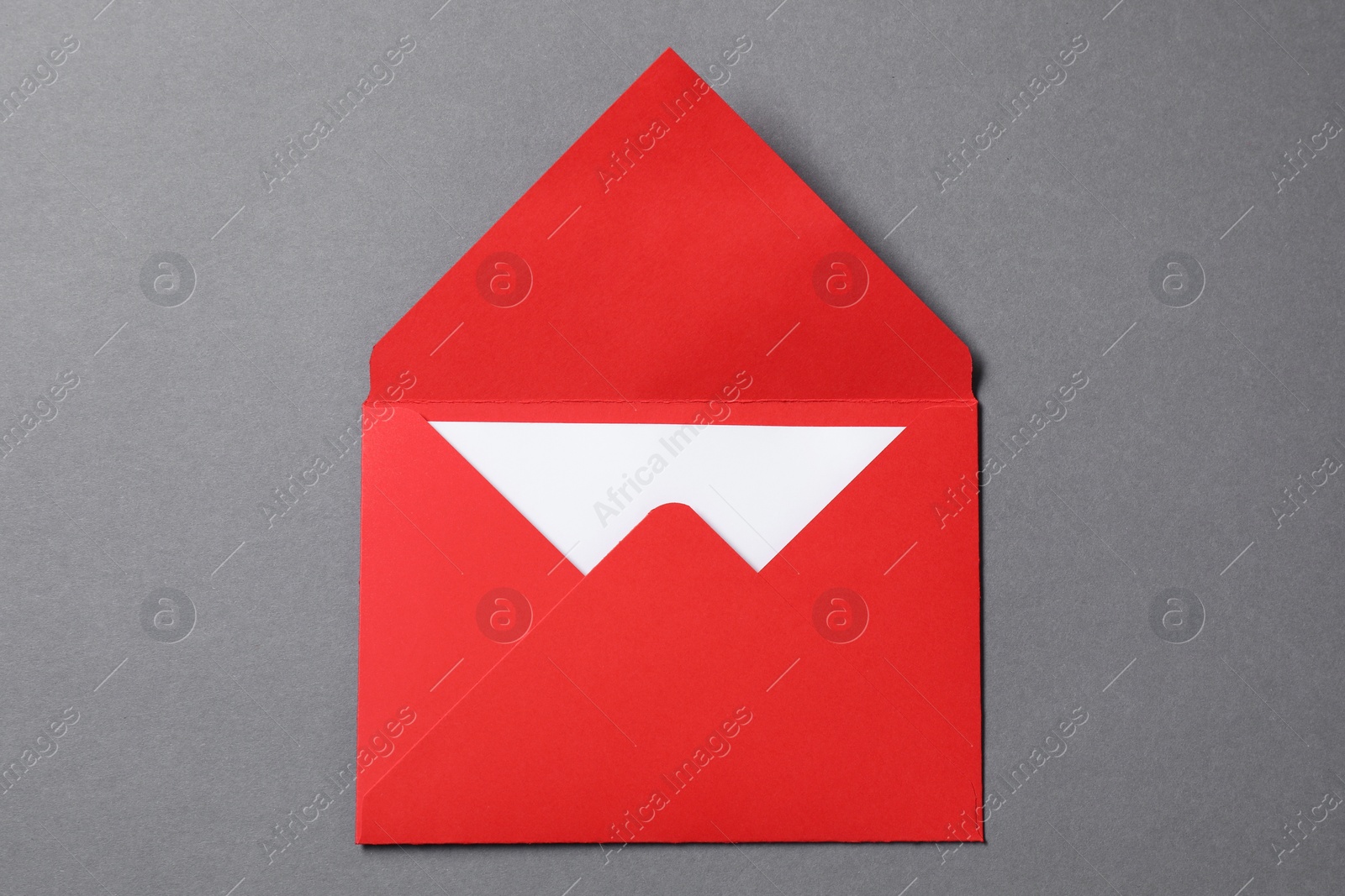 Photo of Blank sheet of paper in open letter envelope on grey background, top view