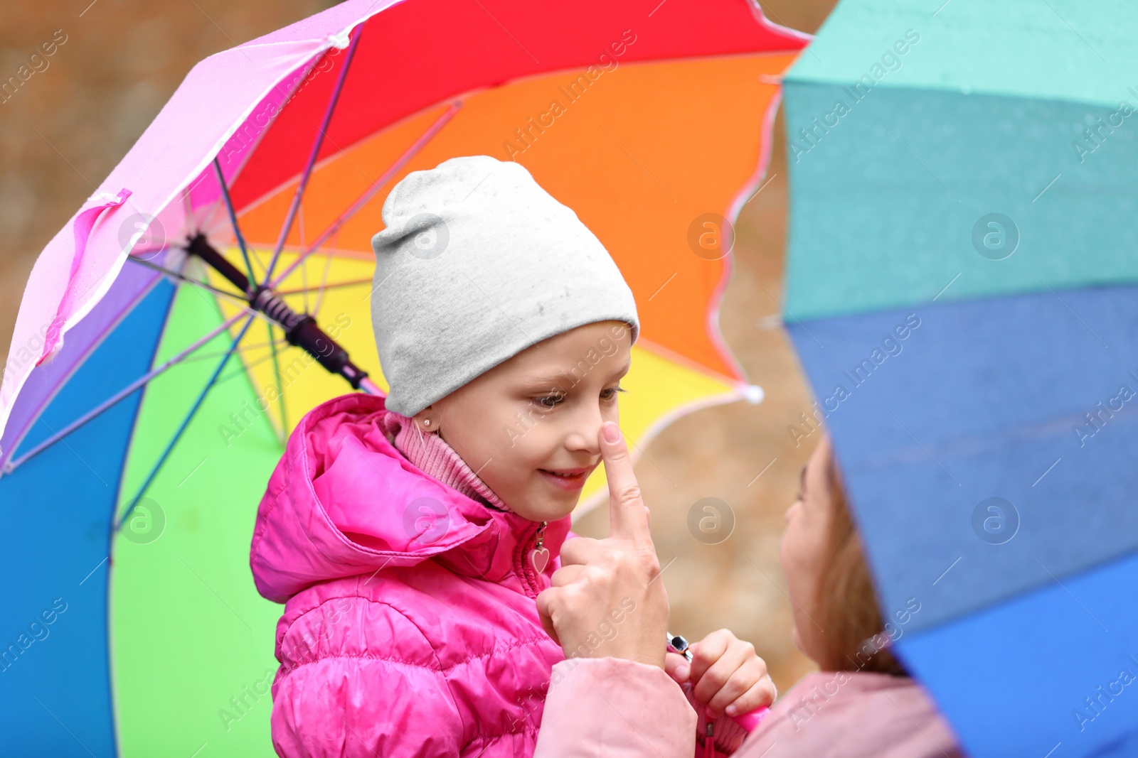 Photo of Mother and daughter with umbrellas outdoors on autumn rainy day