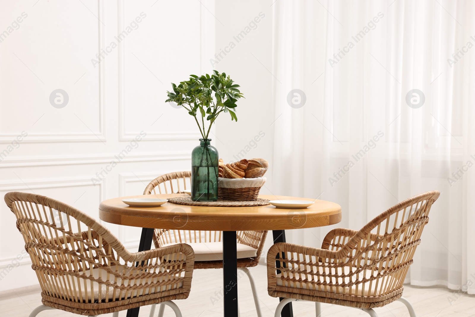 Photo of Dining room interior with comfortable furniture and green branches