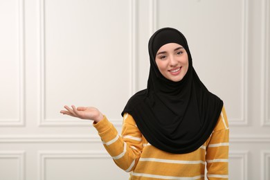 Muslim woman in hijab pointing at something indoors