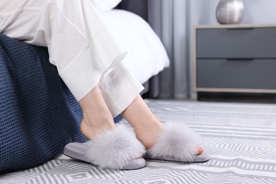 Woman in grey soft slippers at home, closeup. Space for text