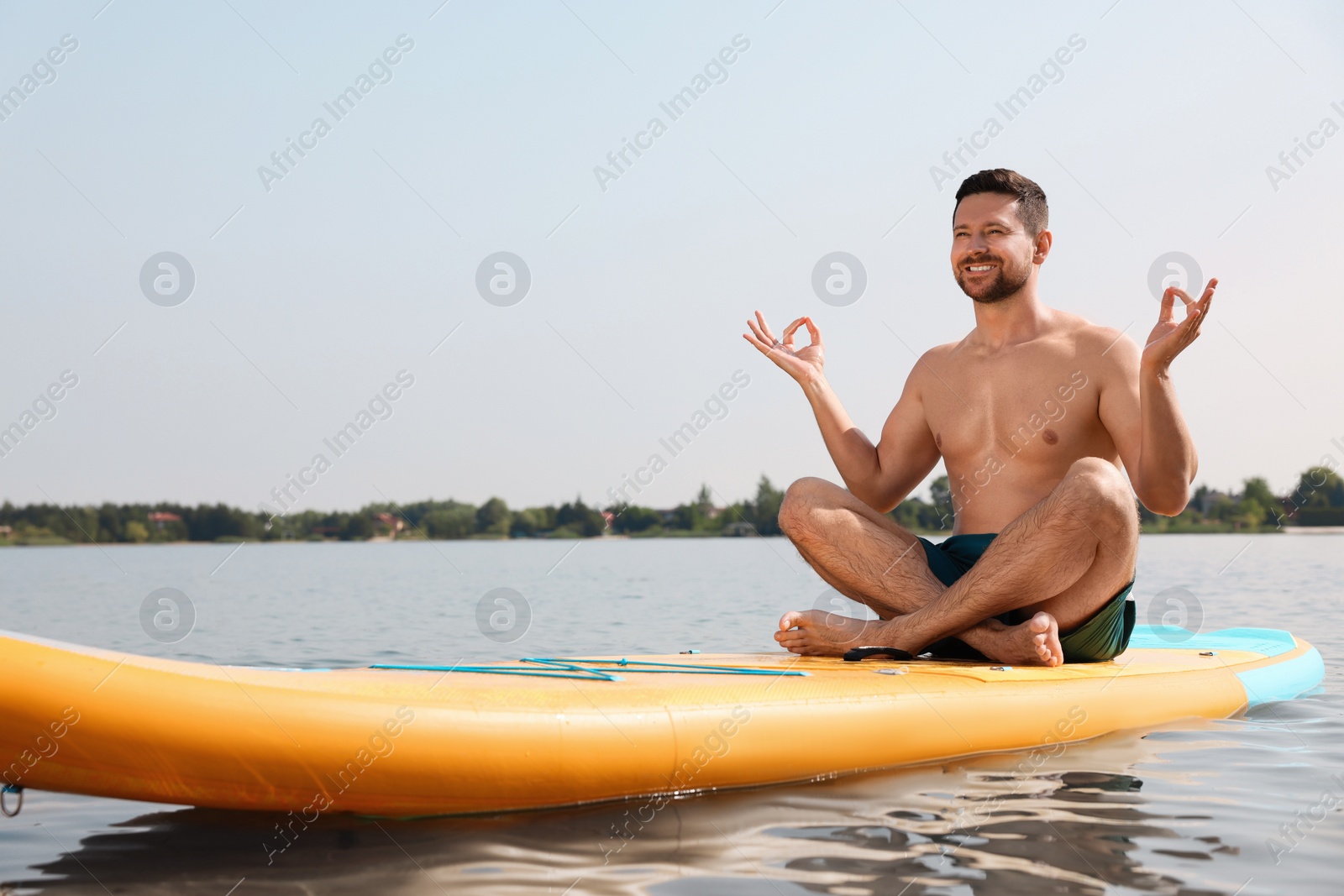 Photo of Man practicing yoga on SUP board on river