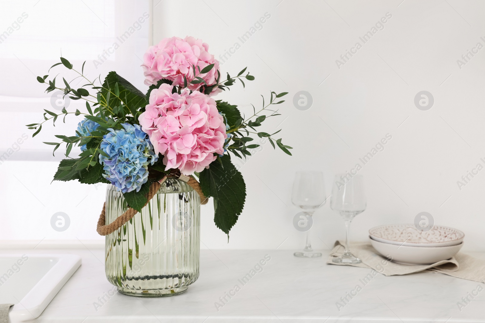 Photo of Beautiful hortensia flowers in vase on kitchen counter. Space for text