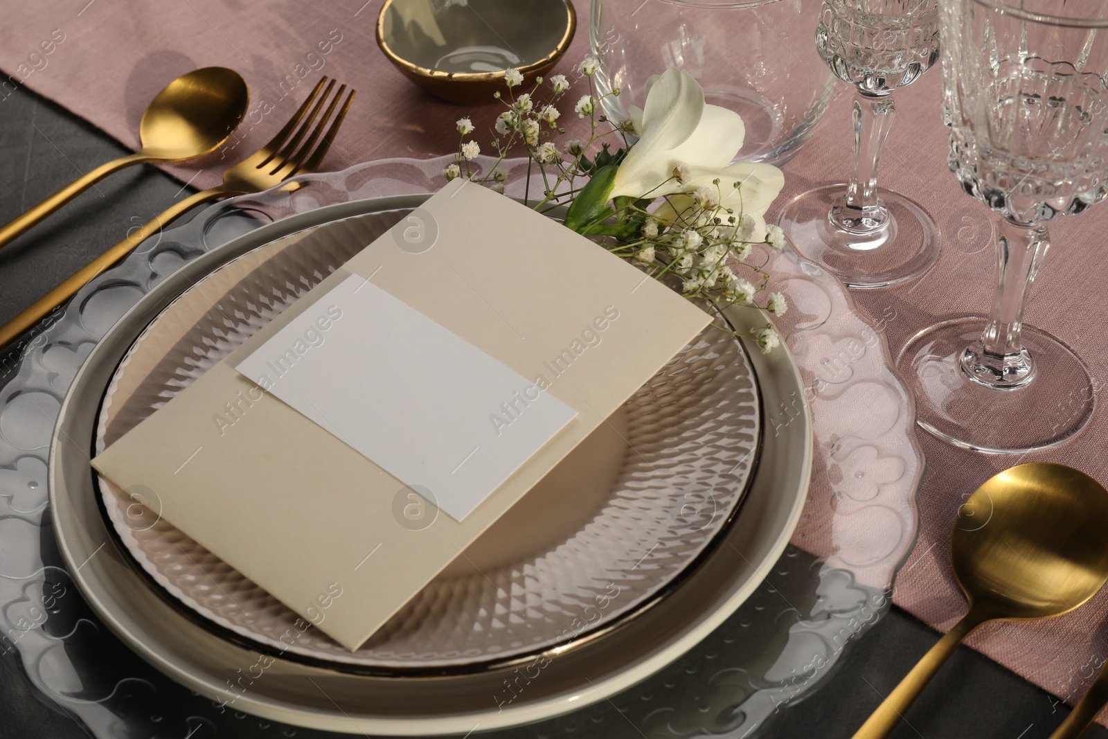 Photo of Stylish table setting. Dishes, cutlery, blank card and floral decor, closeup