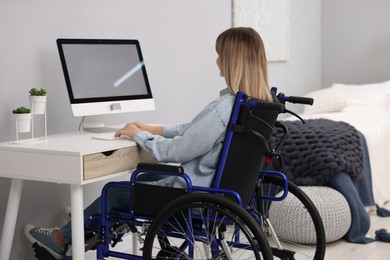 Photo of Woman in wheelchair using computer at table in home office