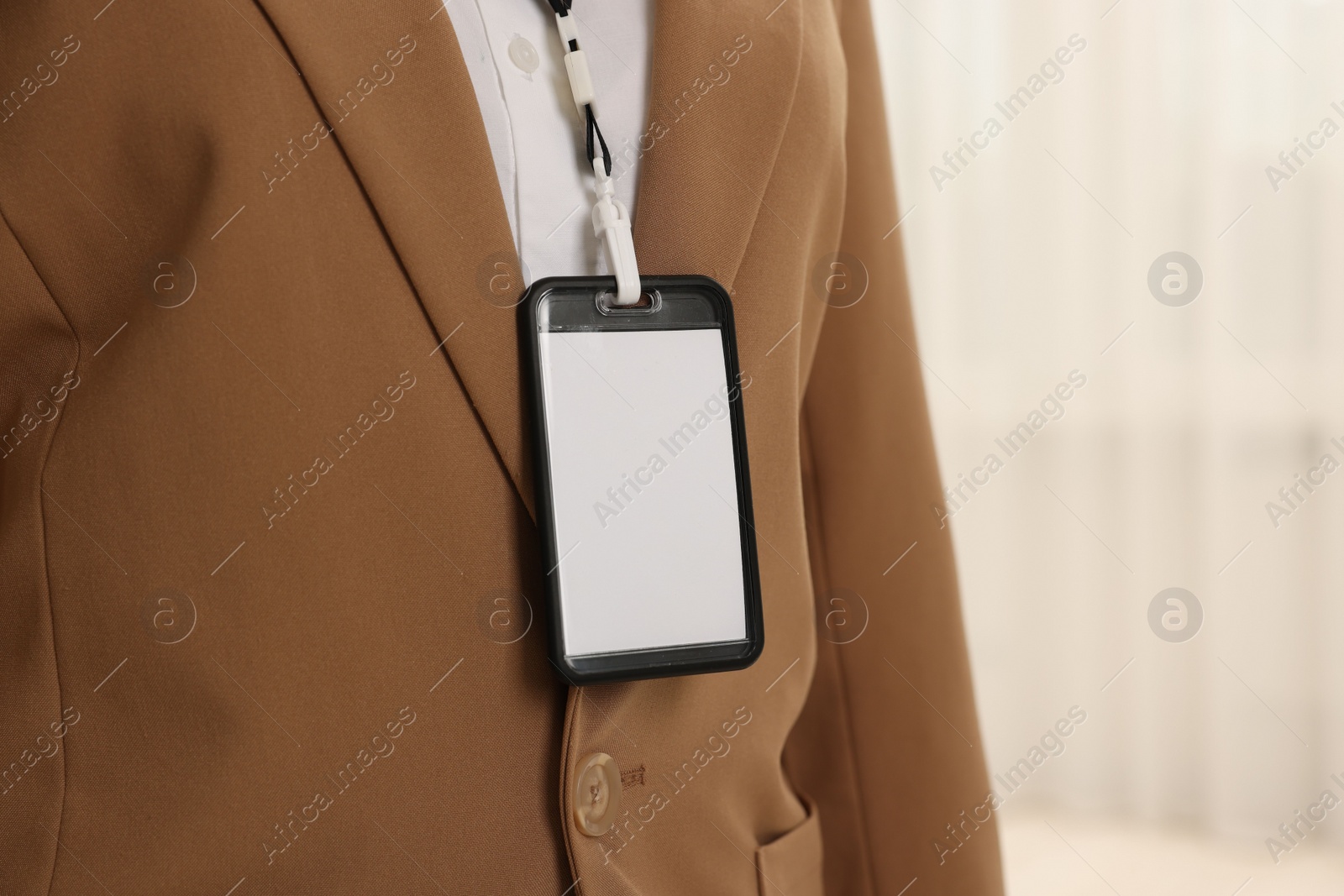 Photo of Woman with blank badge indoors, closeup. Space for text