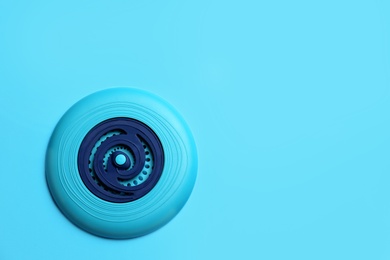 Plastic frisbee disk on light blue background, top view. Space for text