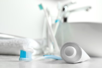 Plastic toothbrush with paste and tube on white countertop in bathroom, closeup. Space for text