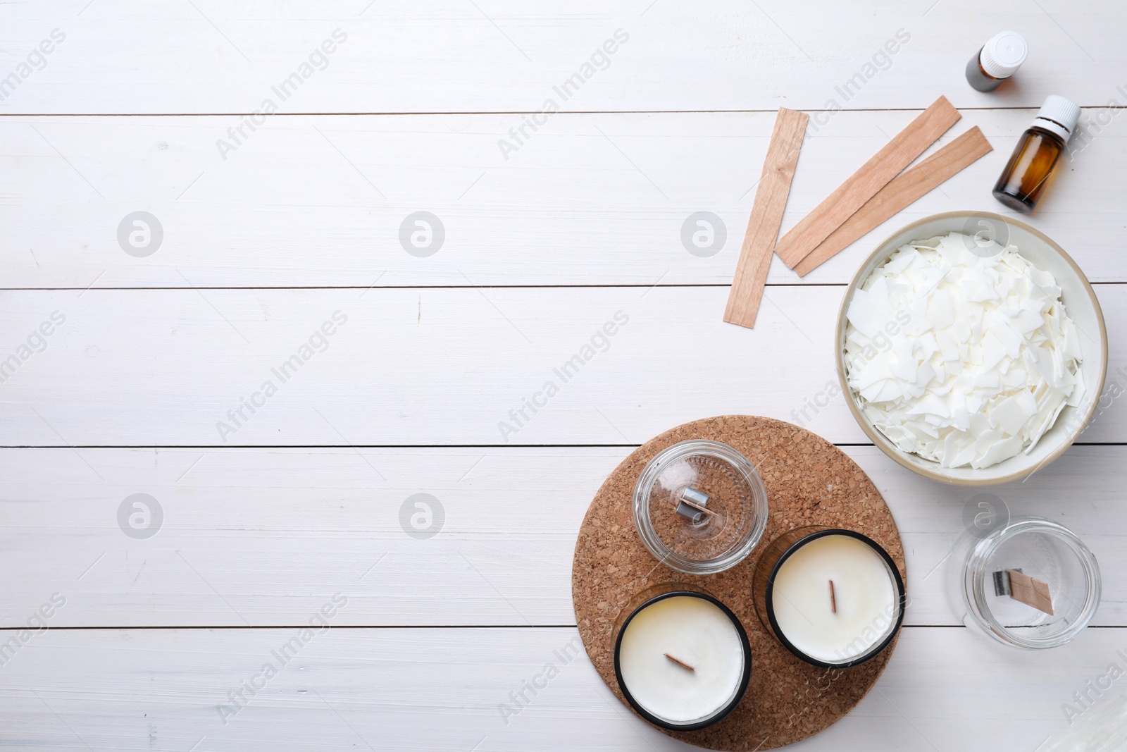 Photo of Flat lay composition with homemade candles and ingredients on white wooden background, space for text