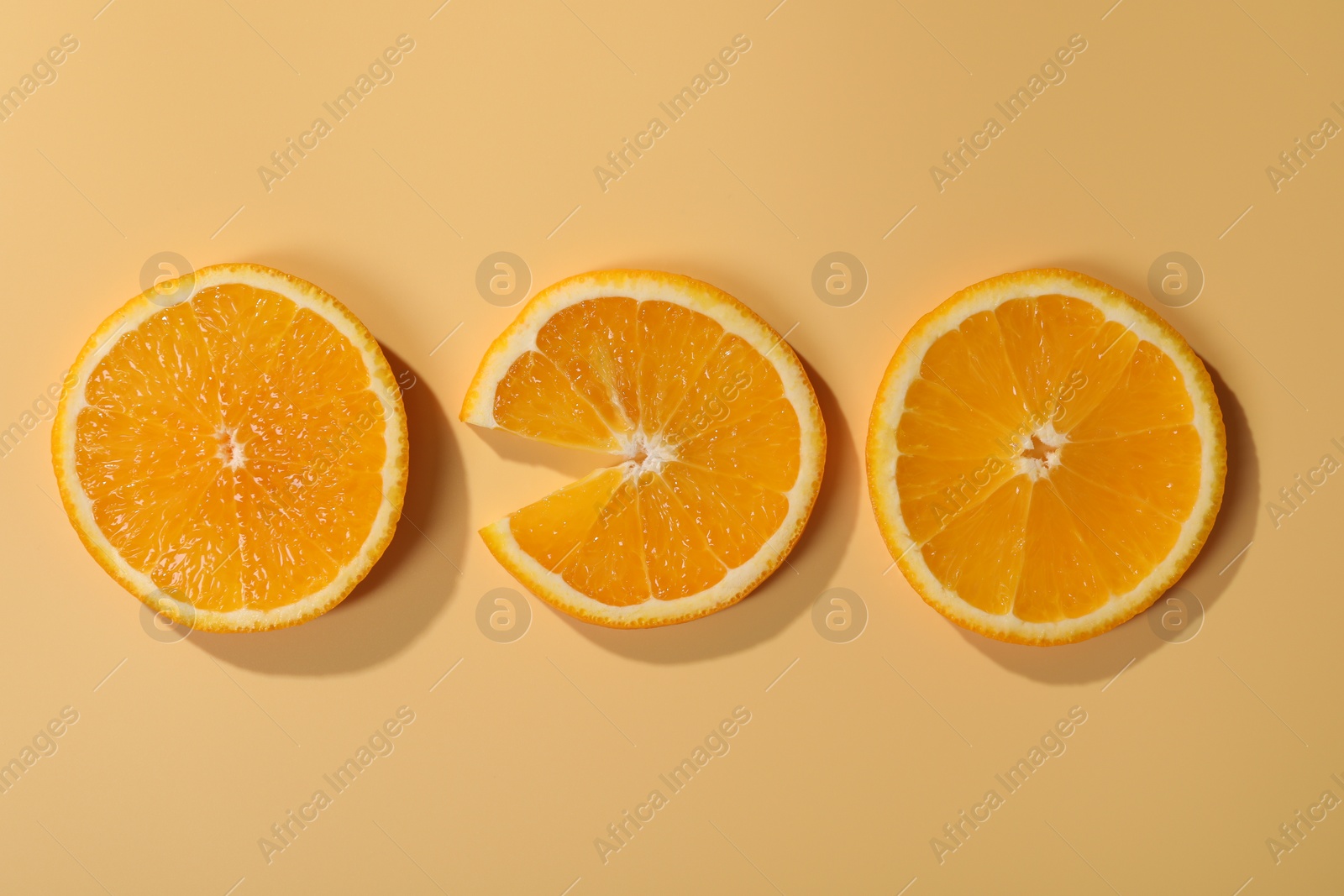 Photo of Slices of juicy orange on beige background, flat lay