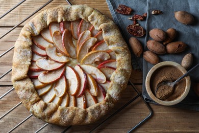 Delicious apple galette, cinnamon and pecans on wooden table, flat lay