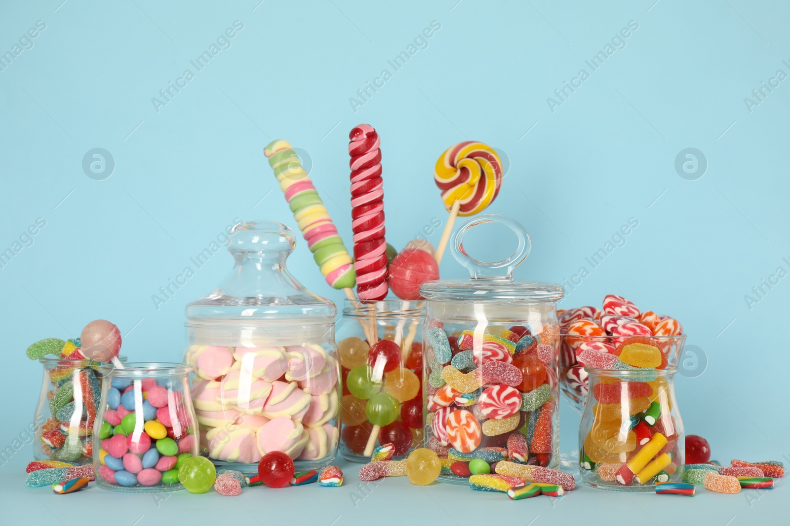 Photo of Jars with different delicious candies on light blue background
