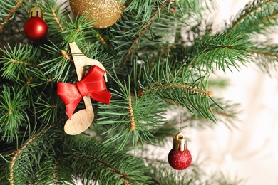 Photo of Fir tree with wooden note and decor, closeup. Christmas music concept