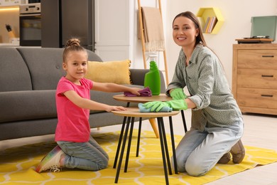Photo of Spring cleaning. Mother and daughter tidying up living room together