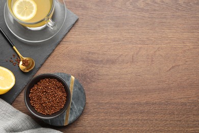 Photo of Buckwheat tea and granules on wooden table, flat lay. Space for text