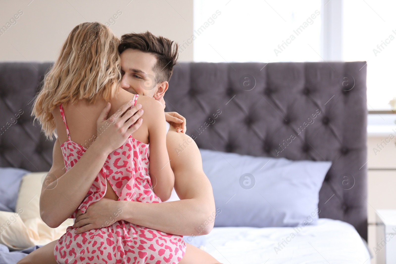 Photo of Happy young couple being intimate on bed at home