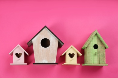 Photo of Collection of handmade bird houses on pink background, flat lay