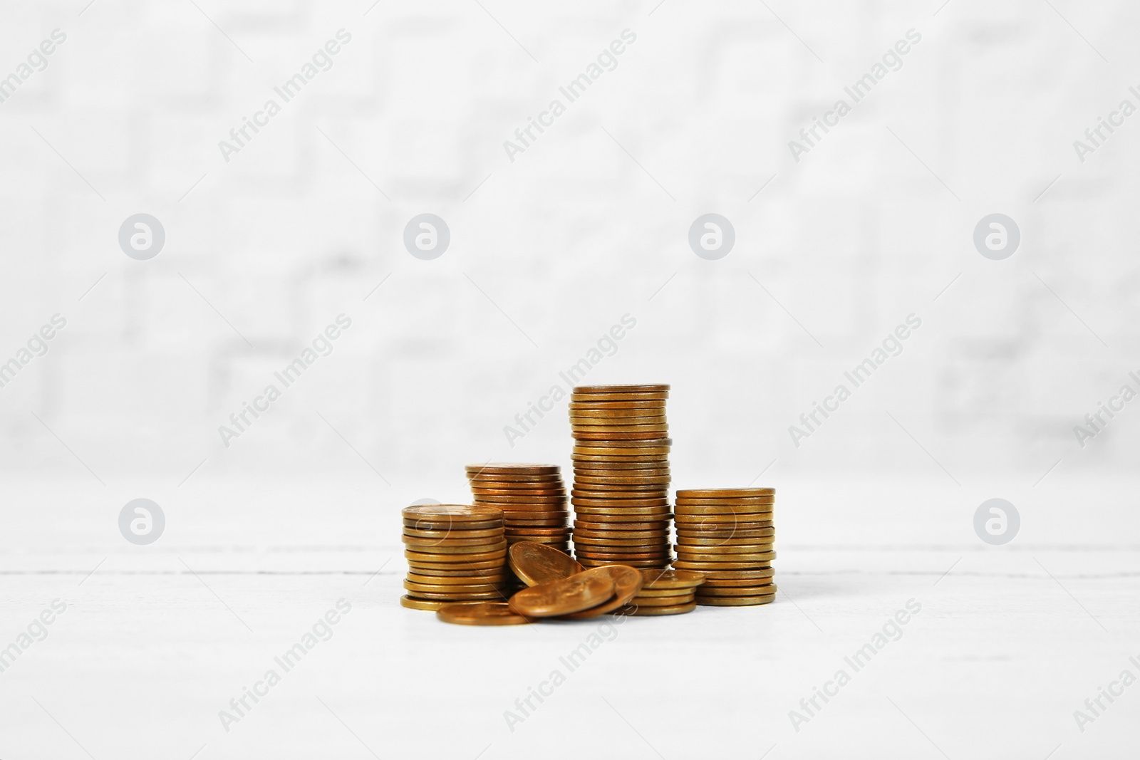 Photo of Many stacks of coins on table against light background