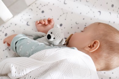 Adorable baby with toy peacefully sleeping in crib