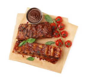 Photo of Tasty roasted pork ribs, sauce, basil and tomatoes isolated on white, top view
