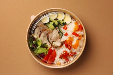 Photo of Tasty food in container on beige background, top view